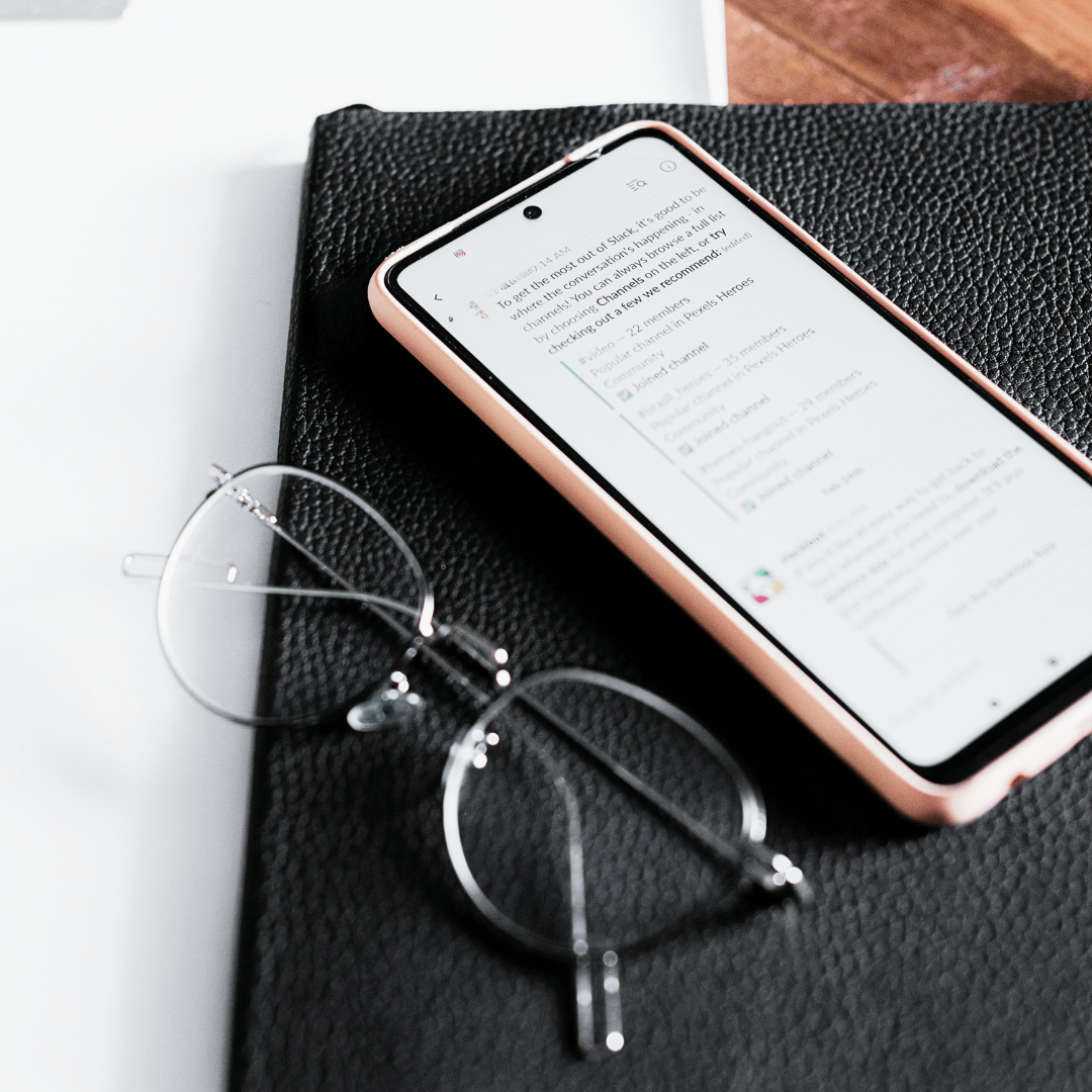 A iPhone sitting onto of a black planner. The cell phone shows social media engagement.