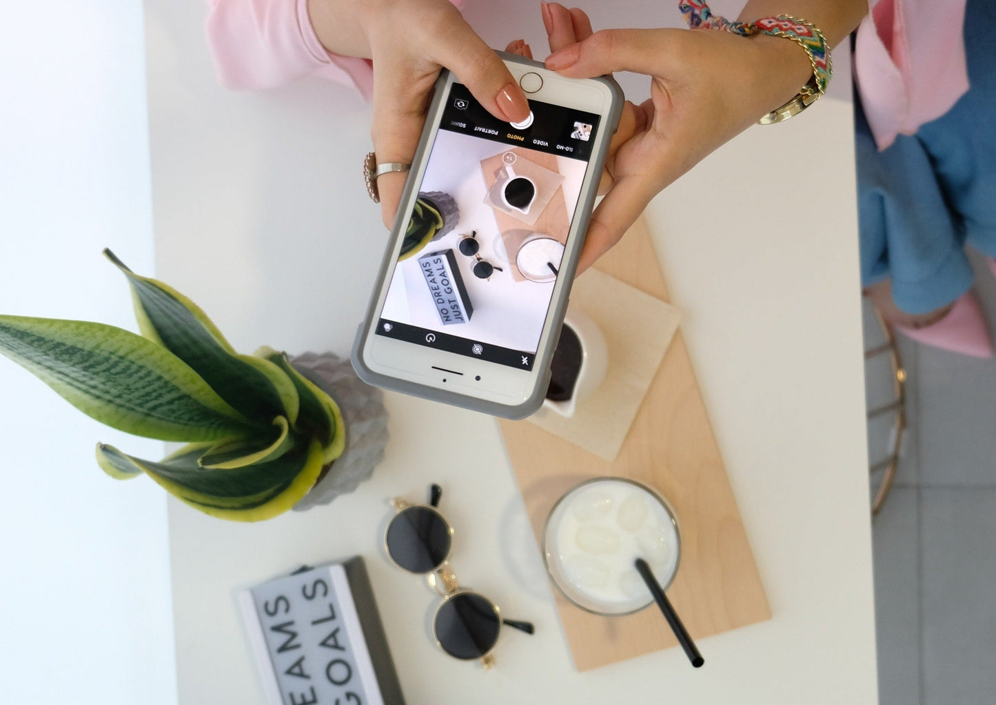 A woman taking pictures of products with an iphone. Product flat lay photography. Image by The Lazy Artist Gallery
