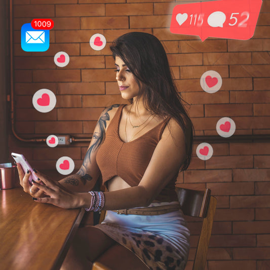 Two Twenty Two Marketing A La Carte Social Media Engagement Management item. A woman sitting at a table using her cell phone to comment, message, and engage on social media platforms Facebook, Instagram, Nextdoor and messenger.  Image by Davila Dalprat