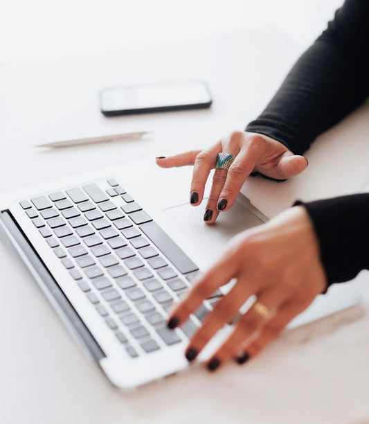 Image of a womans hands using a laptop to do a social media profile bio audit two twenty two marketing