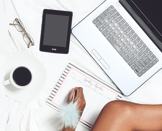 Picture of a woman in bed working on her planner for social media. White bedding, coffee, ipad, fluffy white pen. Trendsetter social media package bundle by Two Twenty Two Marketing. Image by Adrienne Andersen